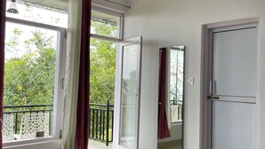A bedroom with a bed, a door, and a window with curtains. - Destination Bir (Baijnath)