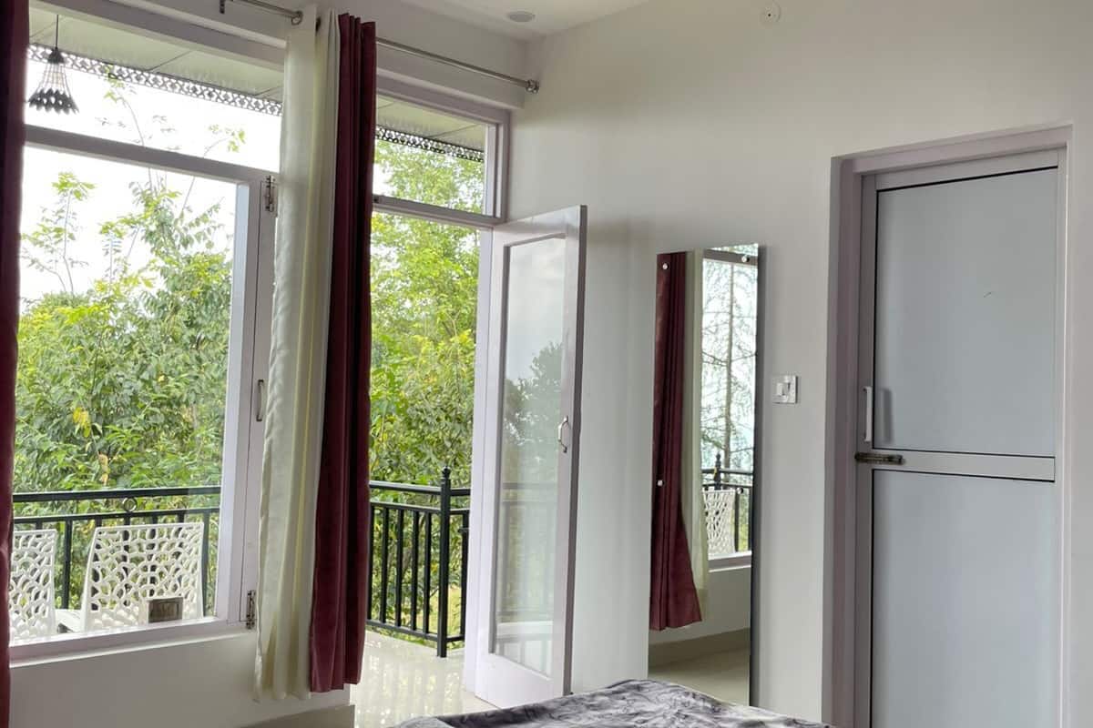 A bedroom with a bed, a door, and a window with curtains.