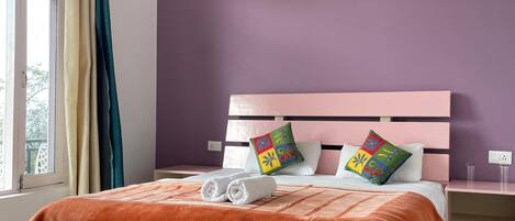 Une chambre à coucher comprenant un lit, une table de chevet, une fenêtre avec des rideaux et un luminaire fixé au mur.