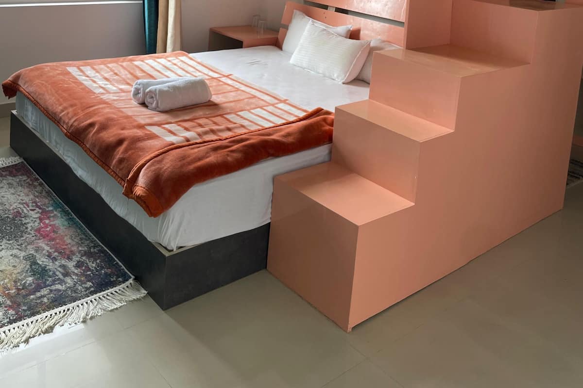 A modern bedroom with a bunk bed, a bedside table, a nightstand, and a window with curtains.
