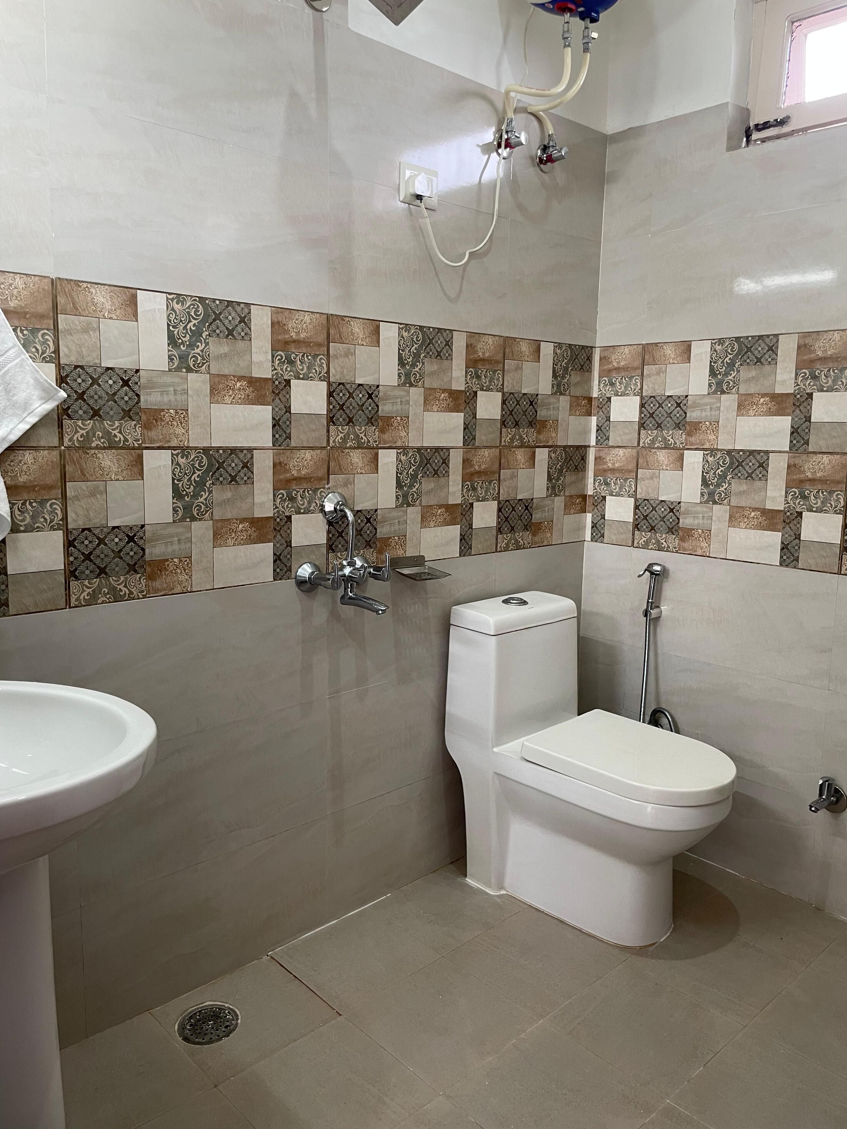 A bathroom with a tiled shower wall, a toilet, and a sink.