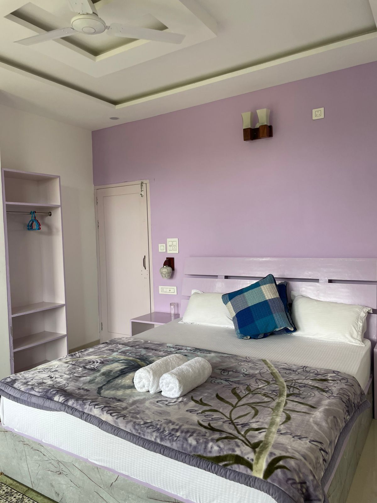 A bedroom with a bed, a wardrobe, a ceiling fan, and a nightstand.