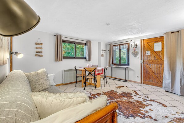 Una habitación acogedora con una cama, una mesa de comedor con sillas, una puerta de madera y vistas al exterior.