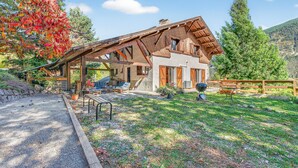 Un bâtiment de style chalet, doté d’un toit en pente, de fondations en pierre et d’une terrasse en bois.