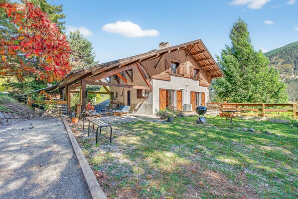 Un bâtiment de style chalet, doté d’un toit en pente, de fondations en pierre et d’une terrasse en bois.