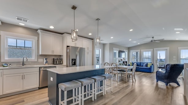 A spacious kitchen with a central island, bar stools, and a dining area with a blue sofa and chairs. - A Wave From It All.  Great location-short walk to beach and Kure Beach Pier. (Kure Beach)