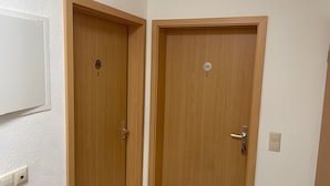 Two wooden doors with a lock and a keyhole, a light switch, and a wall-mounted light fixture.