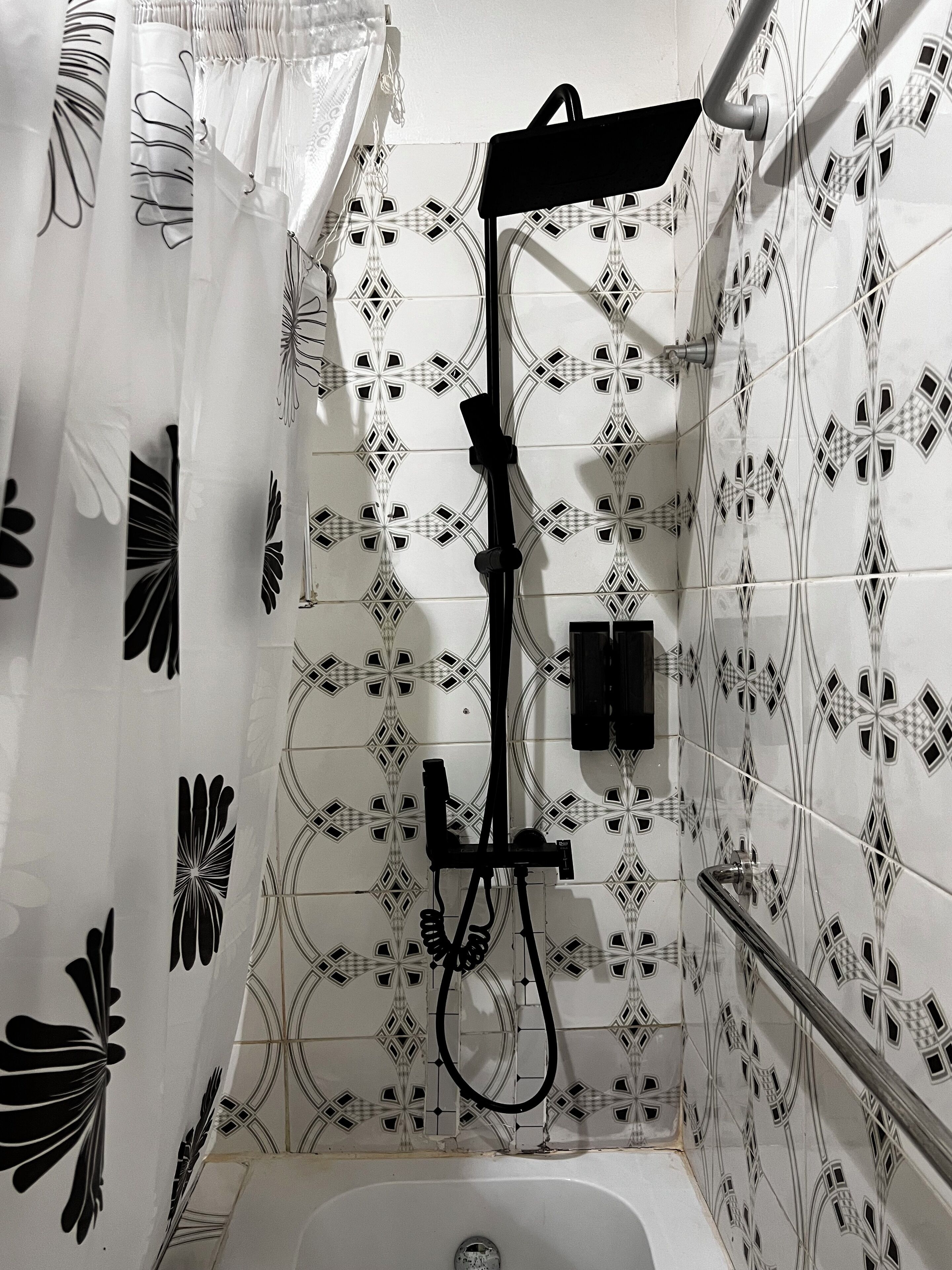 A shower with a handheld showerhead, a handheld showerhead, and a handheld showerhead.