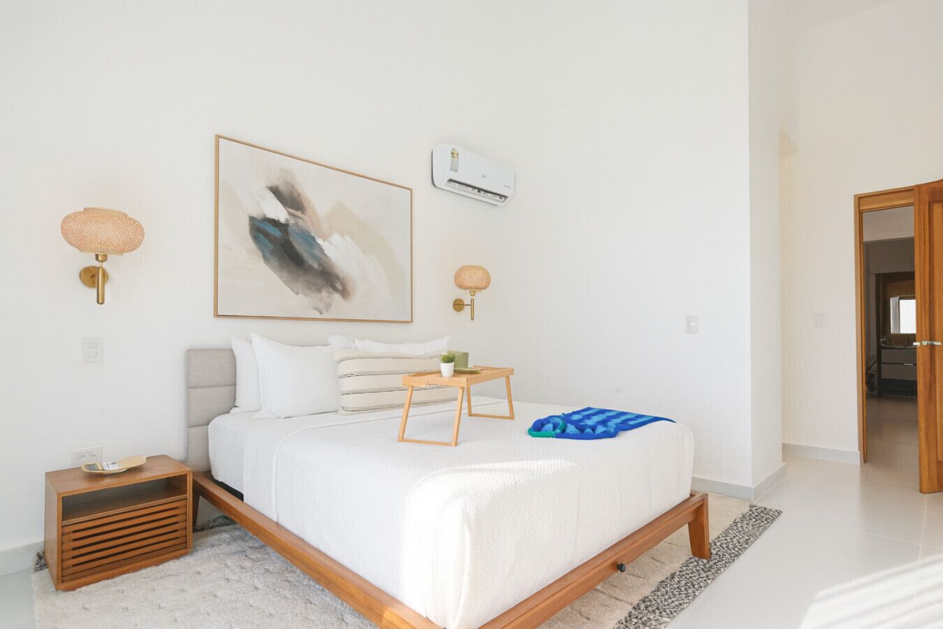 Un dormitorio moderno con cama, mesitas de noche, aire acondicionado de pared y un cuadro.