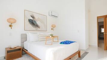 Un dormitorio moderno con cama, mesitas de noche, aire acondicionado de pared y un cuadro.