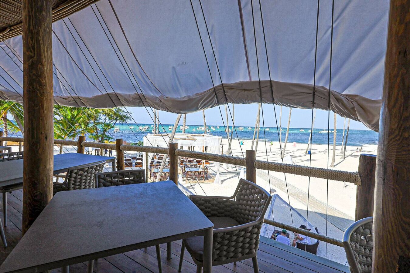 Un área de estar al aire libre con mesas y sillas con vista a una playa y al mar.