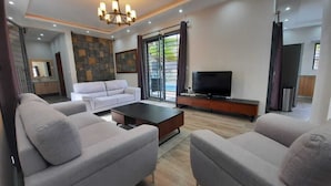 Una sala de estar moderna con un conjunto de sofás, una mesa de centro, un televisor y una pared decorativa de piedra.