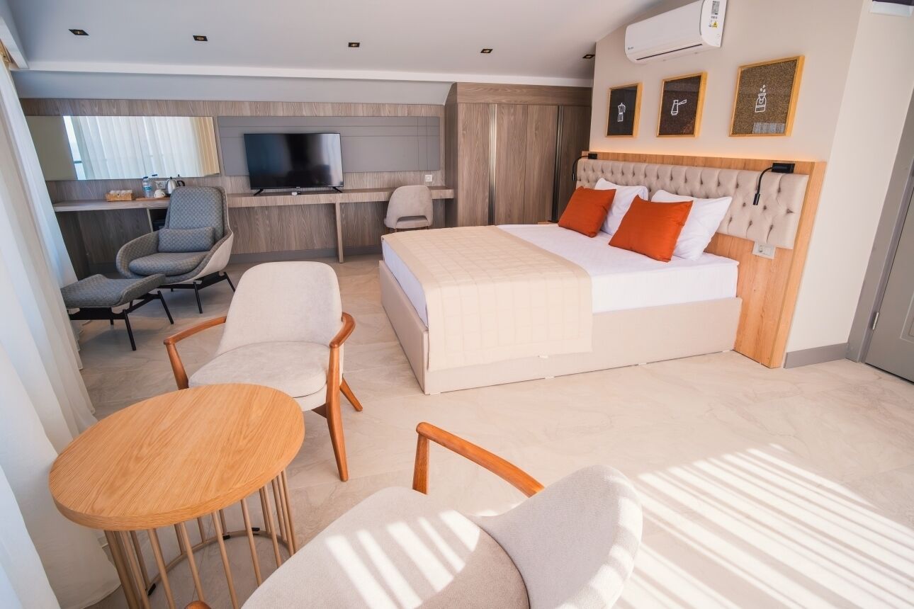 Una habitación de hotel moderna con cama, escritorio, televisor y zona de estar con mesa y sillas.