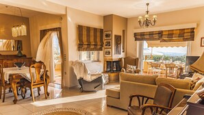 A spacious living room with a fireplace, dining area, and a view of the outdoors. - Ktima KiKa - Private Pool Escape & Tranquility (Memi)