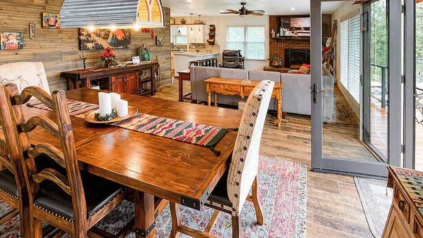A spacious kitchen with a dining area, a fireplace, and a large sliding glass door leading to a balcony. - Constancio's Cabin (Ruidoso)