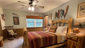 A bedroom with a wooden bed, a rocking chair, a nightstand, a lamp, and a ceiling fan. - Constancio's Cabin (Ruidoso)
