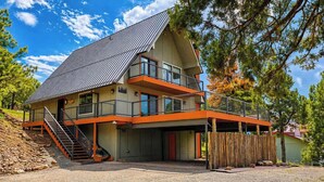 A two-story building with a sloped roof, a balcony on the upper floor, and a staircase leading to the entrance. - Constancio's Cabin (Ruidoso)
