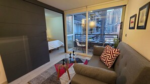 A modern living room with a sofa, a glass table, and a view of a cityscape through large windows. - Oceana Suites Santa Rosa (Santiago)