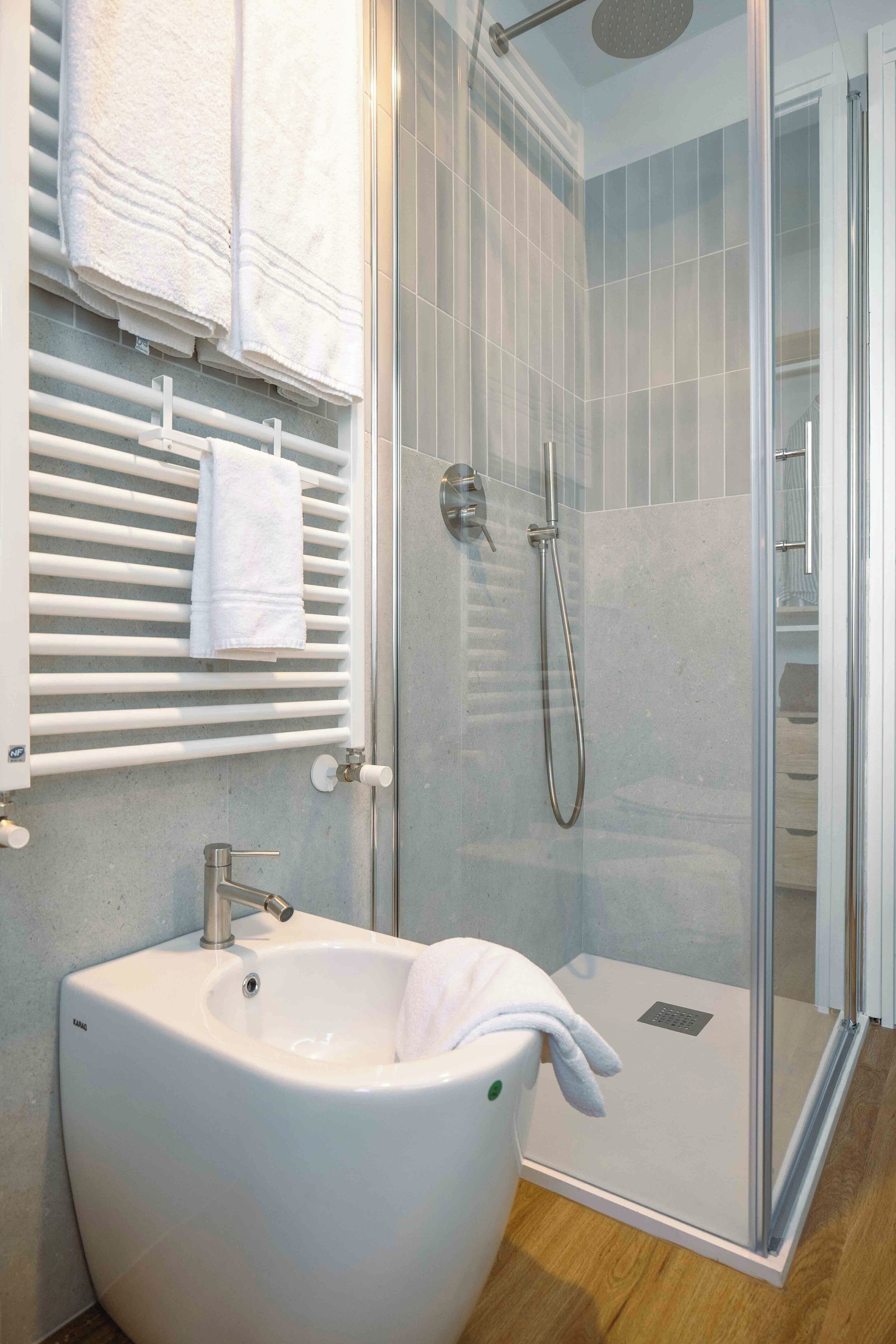 A modern bathroom with a glass-enclosed shower, a white sink, and a towel rack.