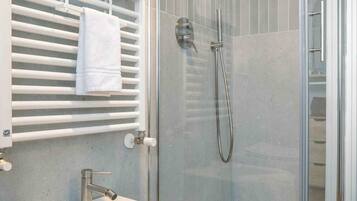 A modern bathroom with a glass-enclosed shower, a white sink, and a towel rack.