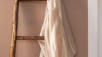 A wooden ladder leaning against a wall with a white shirt hanging on it.