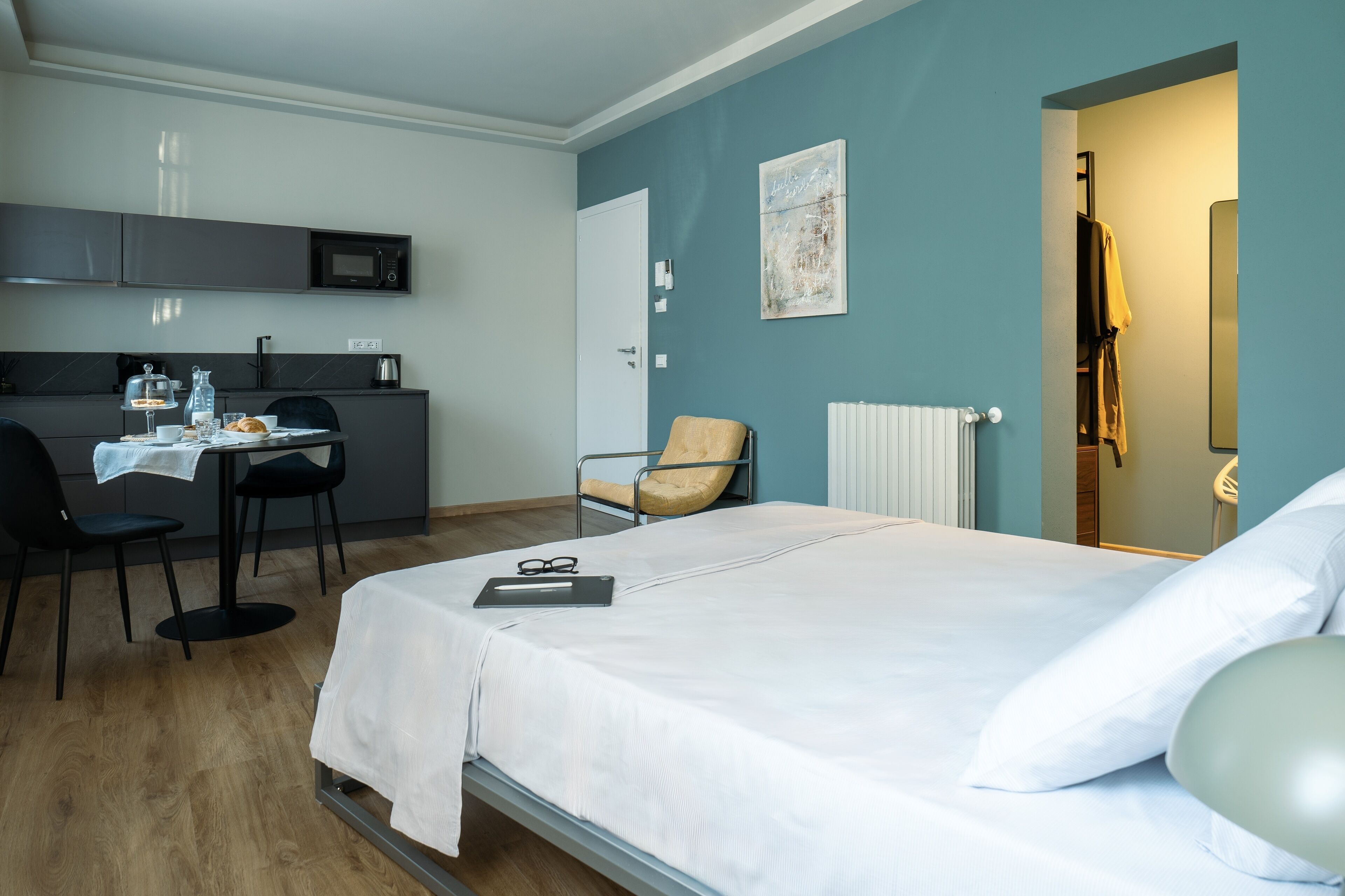 A hotel room with a bed, a desk with a chair, a microwave, and a radiator.