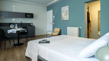 A hotel room with a bed, a desk with a chair, a microwave, and a radiator.