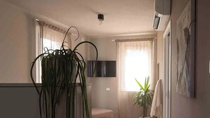 A hotel room with a bed, a potted plant, a TV, and a painting on the wall. - La Croce Apartments (Castelnovo ne' Monti)