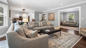 A spacious living room with a grey sofa set, a coffee table, and a patterned rug. - Southampton 4BR Home | Heated Pool, Firepit, Large Backyard (Hamptons)