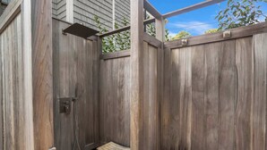 A wooden outdoor shower area with a bench and a showerhead. - Southampton 4BR Home | Heated Pool, Firepit, Large Backyard (Hamptons)