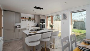 A modern kitchen with a central island, bar stools, and a dining table with chairs.