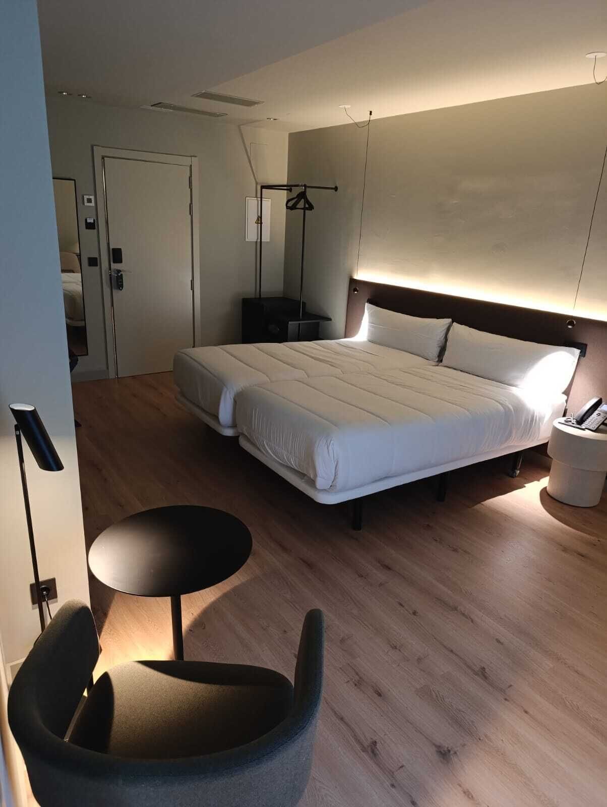 Una habitación de hotel moderna con una cama grande, una mesita de noche, una silla y un armario.