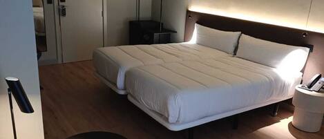Una habitación de hotel moderna con una cama grande, una mesita de noche, una silla y un armario.