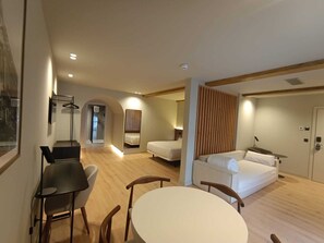 Une chambre d’hôtel moderne dotée d’un coin repas, d’un canapé-lit, d’un bureau et d’un miroir.