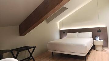 Una habitación de hotel moderna con una cama grande, un escritorio y una mesita de noche.