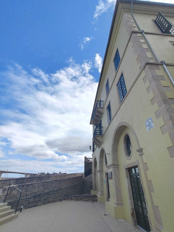 Un bâtiment avec un escalier en pierre menant à une porte, un ciel dégagé et une enseigne sur le mur.