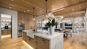 Una cocina moderna con armarios de madera, una isla de mármol e iluminación colgante.