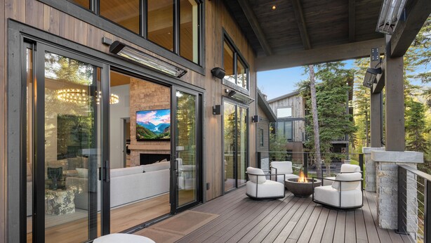 Una terraza moderna al aire libre con una chimenea, zona de estar y puertas de vidrio que dan a un espacio habitable.