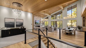 Amplia sala de estar con chimenea, ventanas grandes y una escalera moderna.