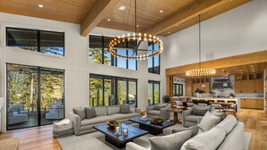 Un amplio salón con grandes ventanales, una cocina moderna y un comedor.