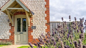 Une petite maison en briques avec une porte verte et une enseigne indiquant « Ash Cottage ».