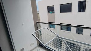 A balcony with a metal railing, a white door, and a view of a building with windows and a door. - Charmant Appart Punique au Cœur de Carthage (Carthage)
