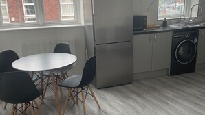 Una cocina moderna con un refrigerador Bosch, una lavadora y un comedor con una mesa redonda y sillas.