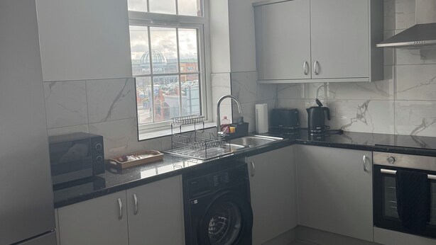 Una cocina moderna con lavadora integrada, microondas y fregadero.