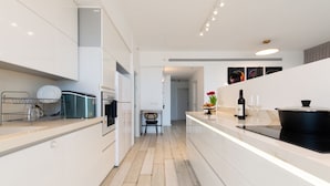 Une cuisine moderne avec des meubles blancs, un îlot central et un coin repas équipé d’une chaise.