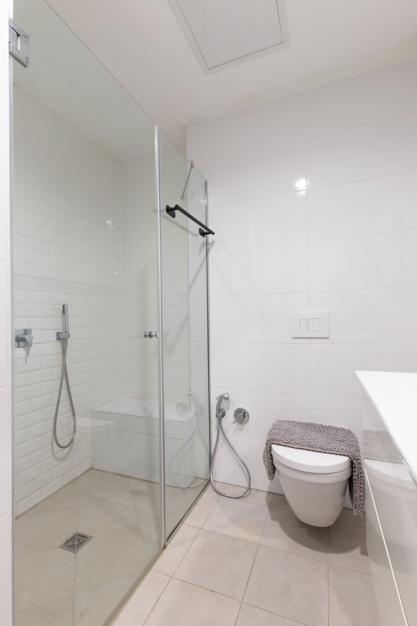 Un baño moderno con ducha de vidrio, inodoro blanco y una toalla colgada en la pared.