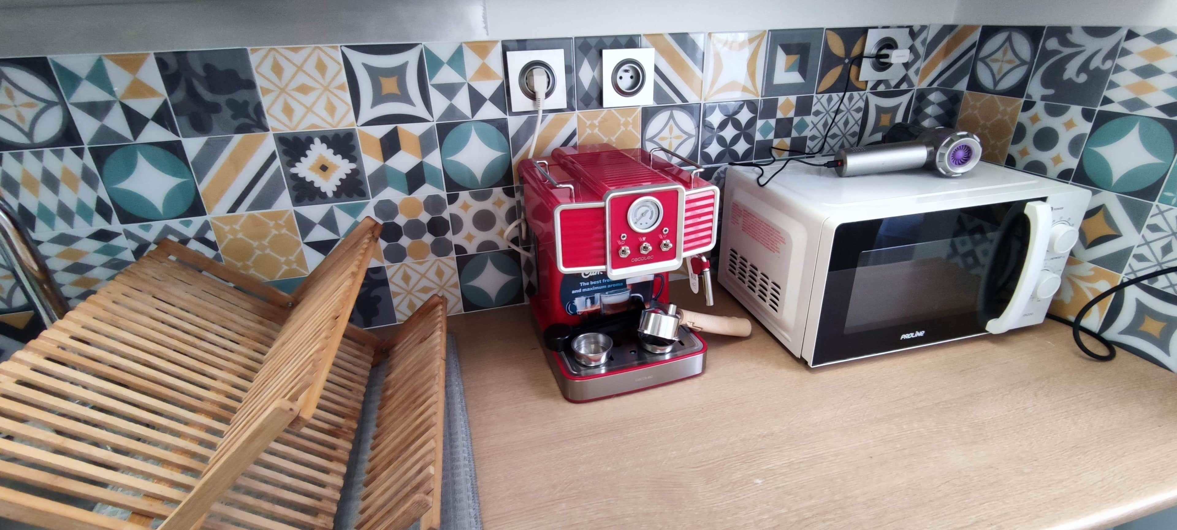 A kitchen with a coffee maker, a microwave, and a wooden rack.