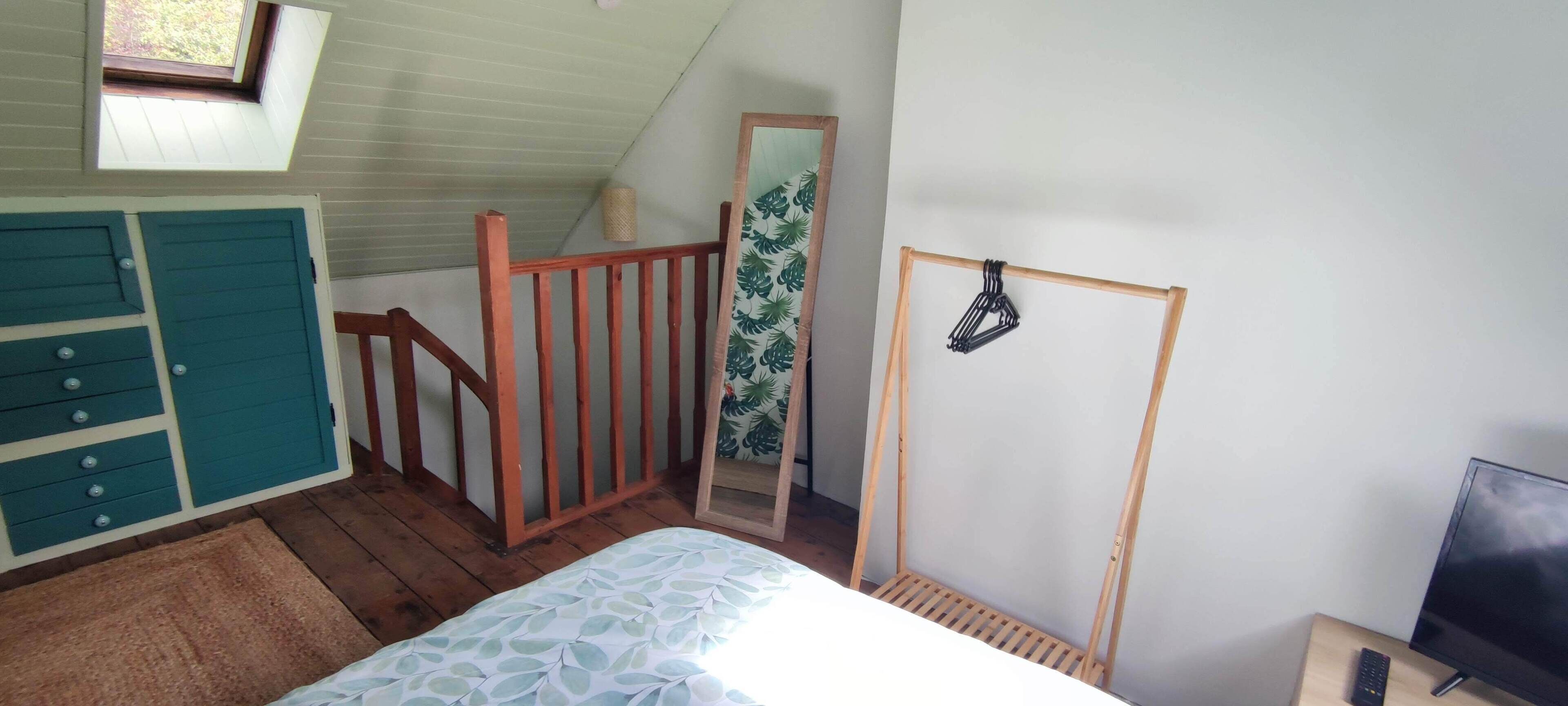 Une chambre à coucher comprenant un lit, une commode, une rambarde en bois, un miroir et un téléviseur.