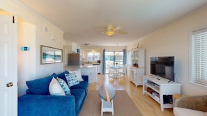 A modern living room with a blue sofa, a small round table, and a television on a white stand.