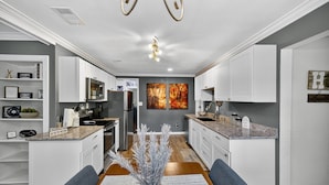 A modern kitchen with white cabinets, granite countertops, and a central island with seating. - Cozy Moultrie Home With Backyard Retreat 3 Bedroom Home (Moultrie)